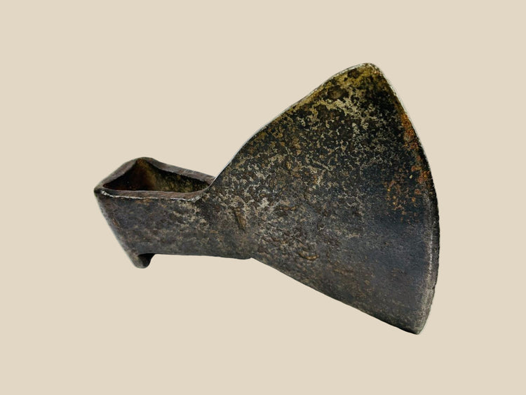 18th-century cast iron axe head from Europe or Colonial America, wedge-shaped with trapezoidal blade, triangular socket, faint punched motif, aged patina, and oxidation, reflecting historical tool craftsmanship.