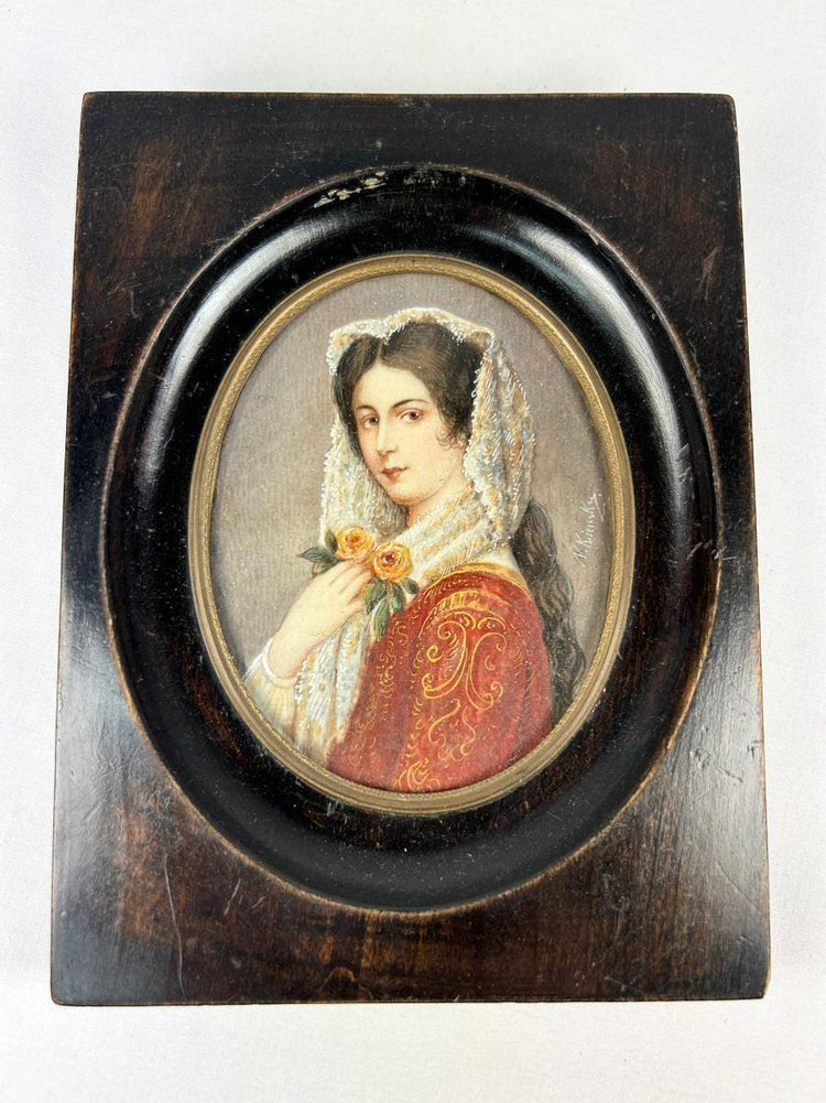 Miniature 19th-century portrait painting of a young woman in red embroidered attire with a lace mantilla, holding two yellow roses, signed “Kimsky,” framed in oval ebonized wood with brass bezel.