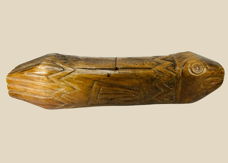 Full side view of hand-carved Melanesian wooden fish drum showing detailed incised patterns