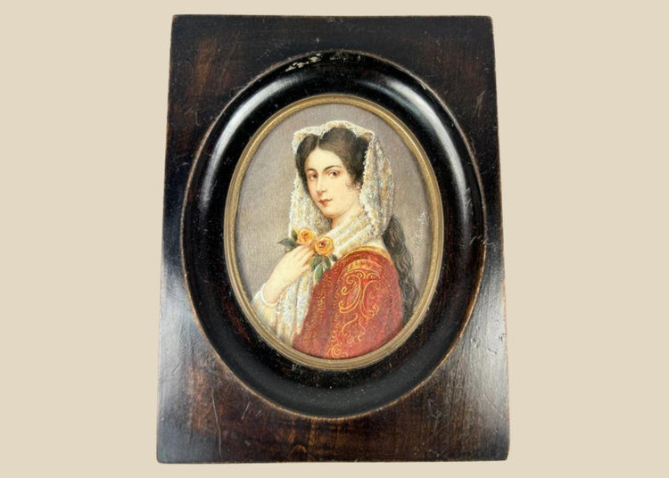 Miniature 19th-century portrait painting of a young woman in red embroidered attire with a lace mantilla, holding two yellow roses, signed “Kimsky,” framed in oval ebonized wood with brass bezel.