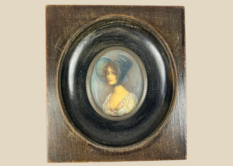 Antique 19th-century Viennese miniature portrait of a woman in blue bonnet and lace gown, painted in gouache on wafer, in original ebonized wooden frame with convex glass.