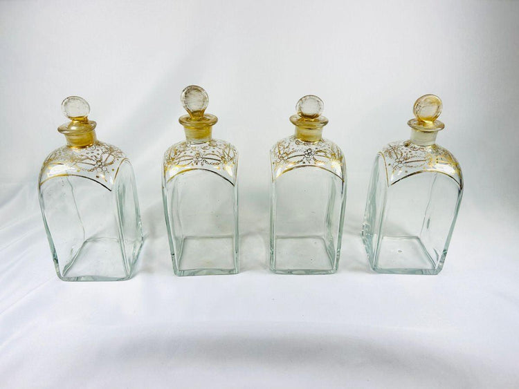 Set of four early Georgian parcel-gilt square glass decanters with matching stoppers displayed upright.