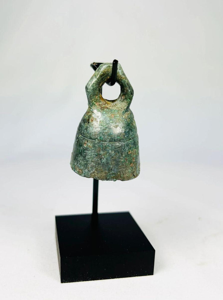 Frontal image of small Roman bronze bell used in religious or domestic settings.