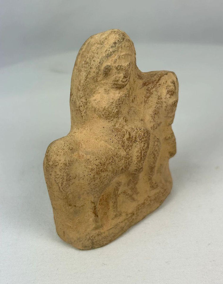Ancient terracotta horse and mounted rider sculpture with worn surface and patina.
