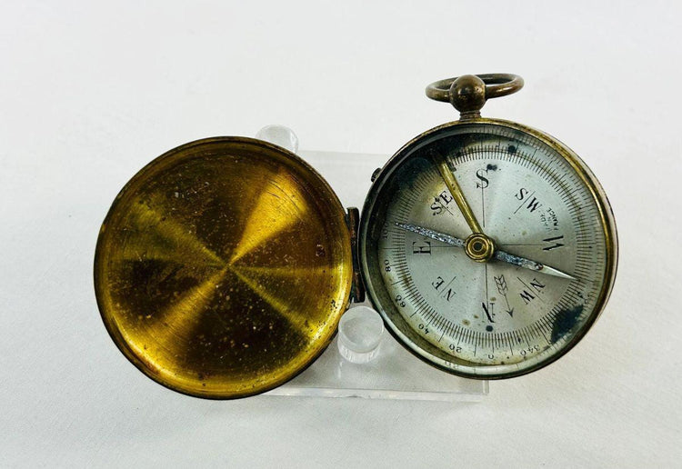 Detail of engraved markings on an antique French brass pocket compass used for navigation.
