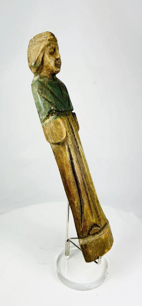 Close-up of carved facial features on antique wooden devotional figurine.