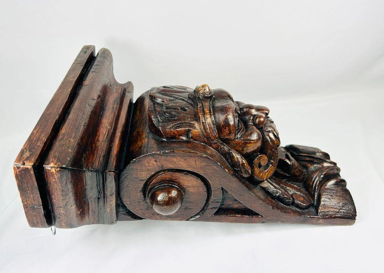 Gothic-inspired wooden corbel with prominent mustache and ornamental details