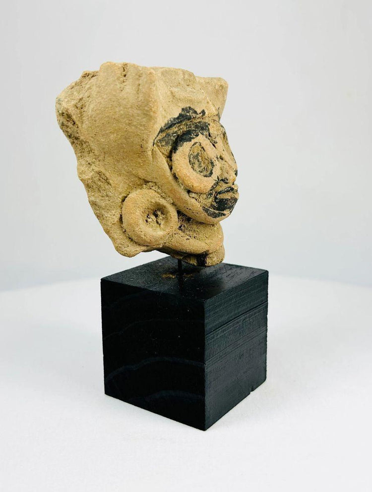 Ceramic head fragment with large circular earrings and traces of black pigment