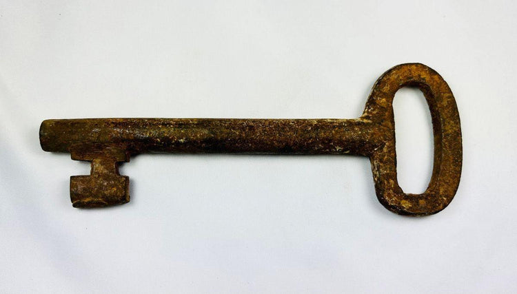 Close-up of 18th-century European iron skeleton key, forged construction with oval handle and aged brown patina, antique warded lock key.