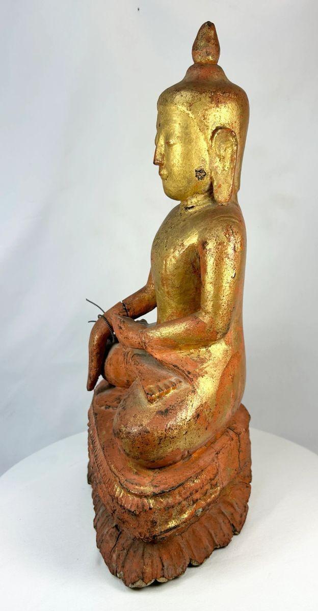 Side profile of a 19th-century Burmese wooden monk statue showing carved robe details