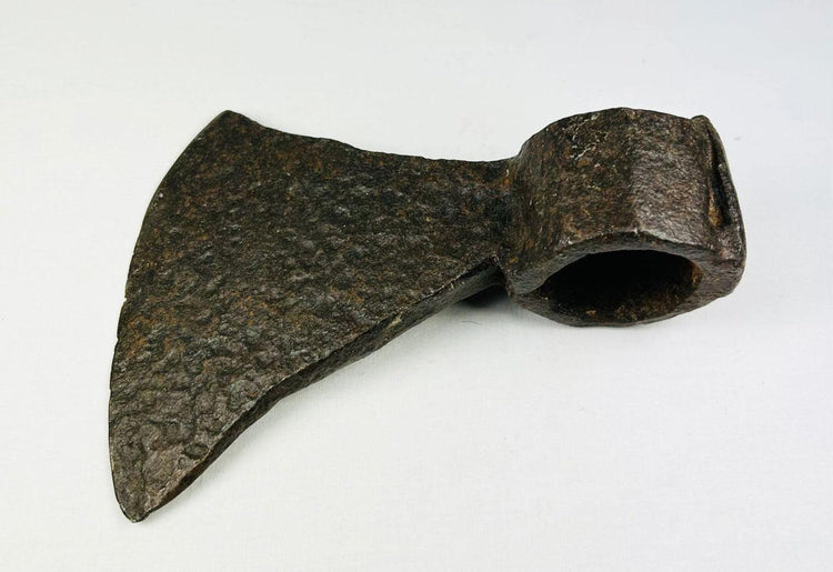 Close-up photo of 19th-century forged iron axe head highlighting blade edge and hammer-worn eye socket.