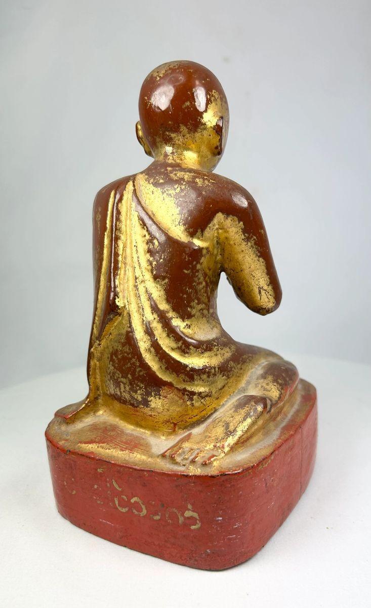 Rear view of hand-carved 19th-century Burmese monk statue, showing aging lacquer and wooden texture.