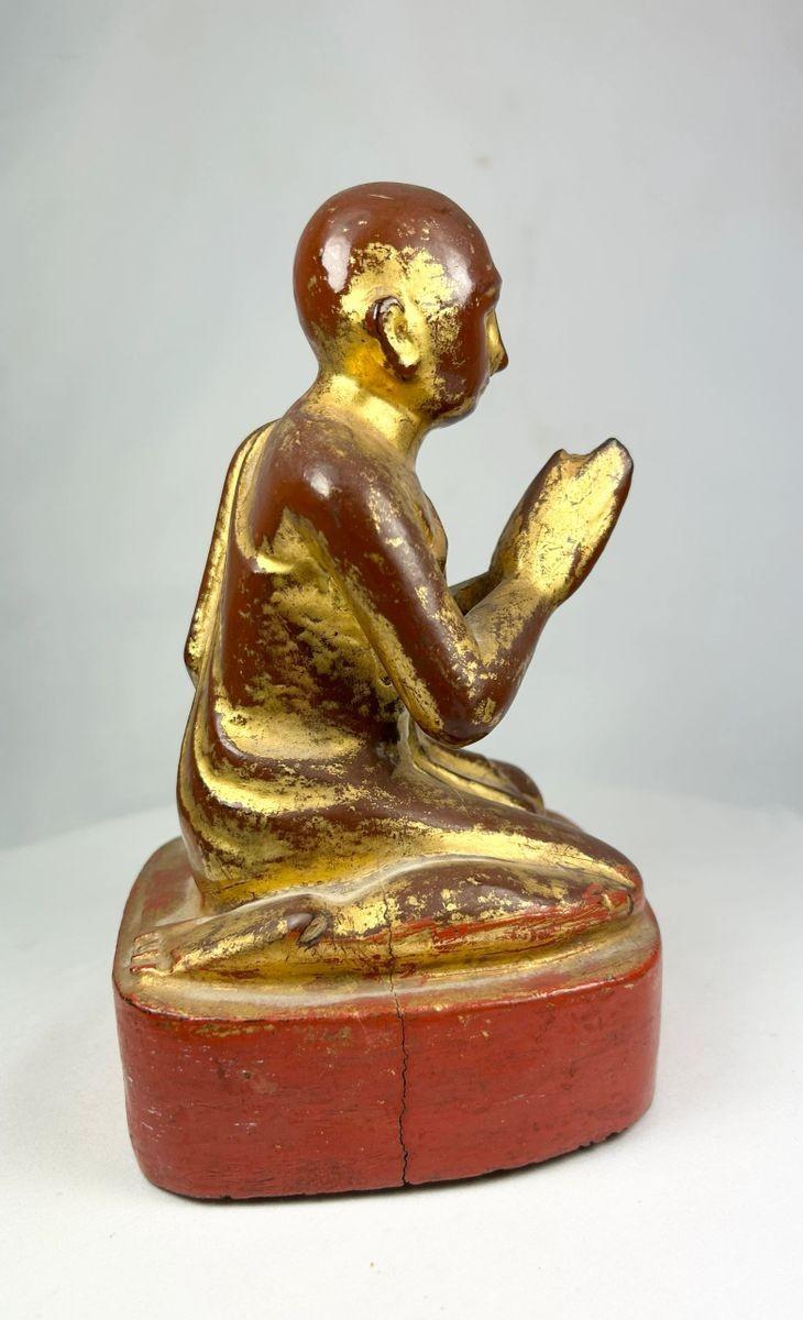 Detailed photograph of gold leaf patterns and carved folds on Burmese monk’s robe.