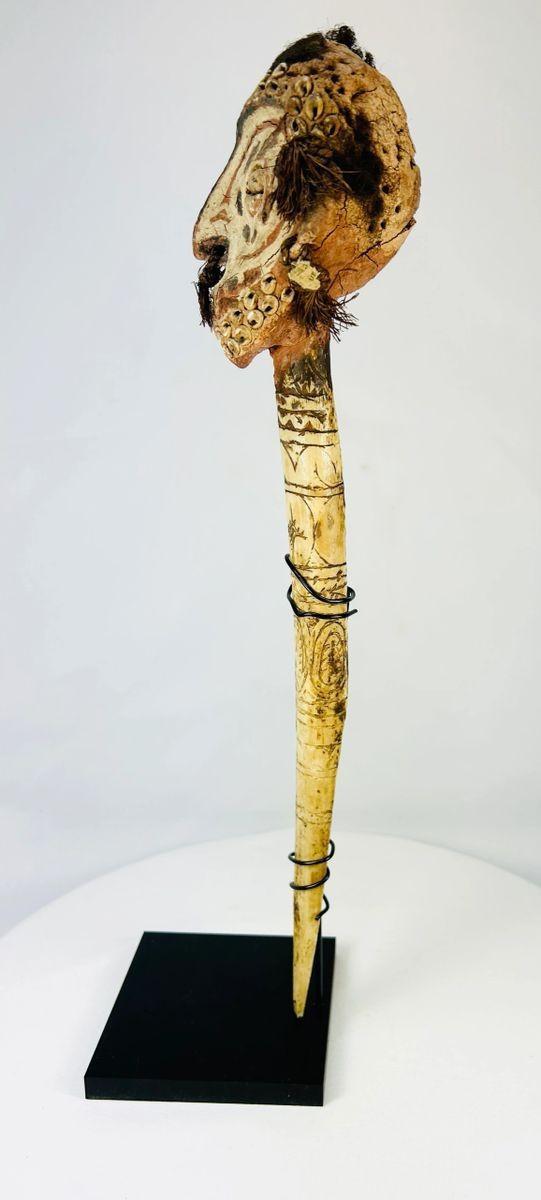 Side profile of Sepik River ceremonial dagger showing elongated bone blade, human hair detailing, and raised tribal carving patterns.