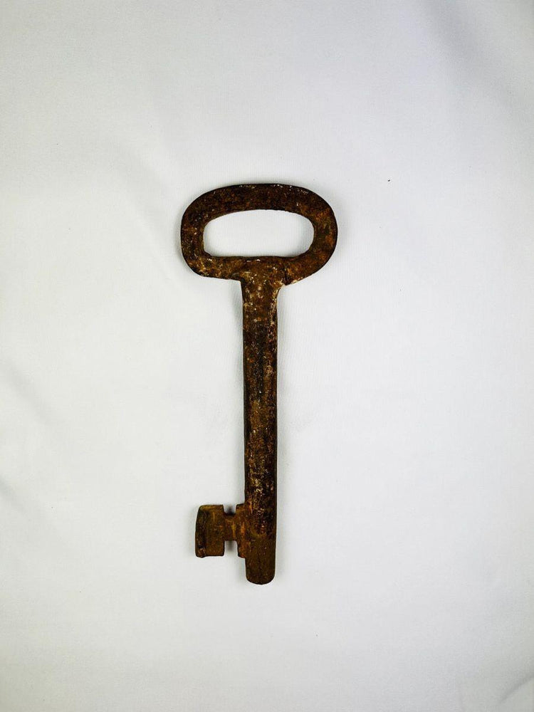 Antique European skeleton key, 18th-century forged iron with distinctive oval bow and corrosion texture, used in estate or castle locks.