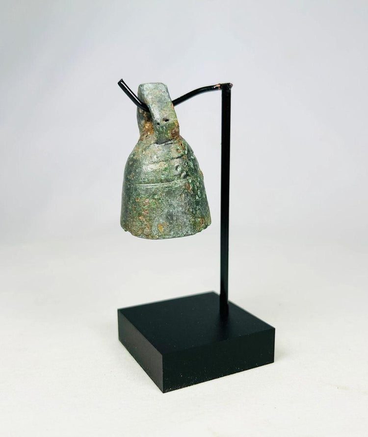 Detailed photograph of Roman bronze bell with worn surface and intact suspension loop.
