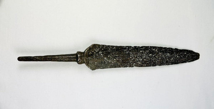 Antique iron spearhead with socketed base and heavy aged patina photographed flat.