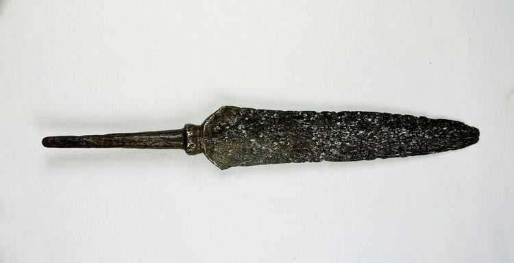 Antique iron spearhead with socketed base and heavy aged patina photographed flat.