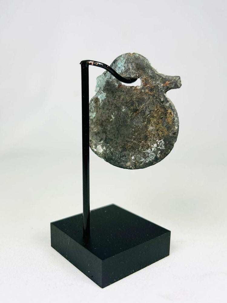 Side view of ancient Roman amulet with soldier motif and aged green patina.