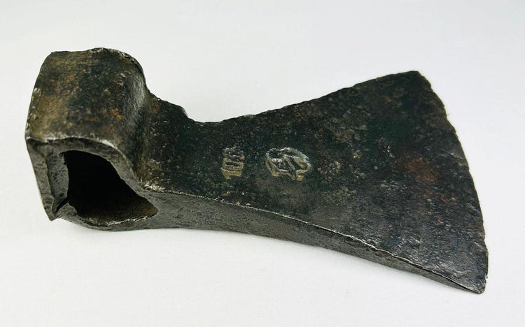 Side view of antique iron axe head with visible markings and aged surface