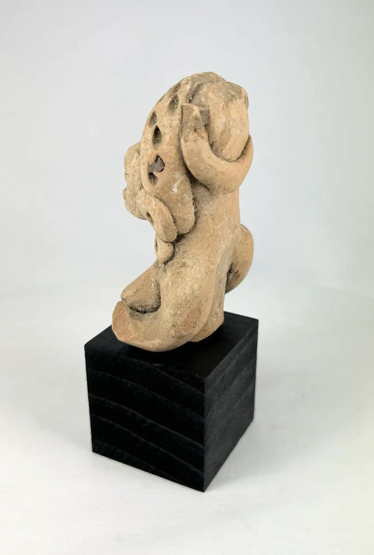 West Mexican terracotta funerary figurine showing a seated woman with pierced eyes and earspools