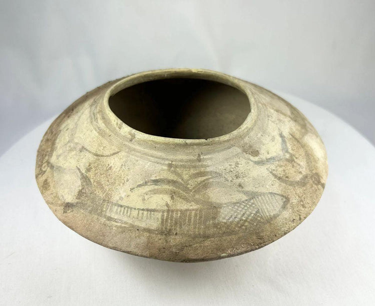 Side view of Indus Valley pottery bowl with symbolic fish motifs and natural clay surface.