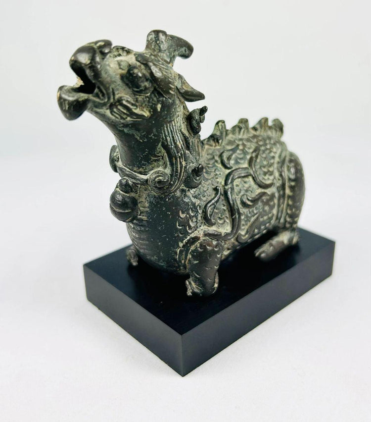 Antique bronze Chi Lin censer, Qing Dynasty era, with raised spine ridges and expressive snarling face, displayed on plinth.