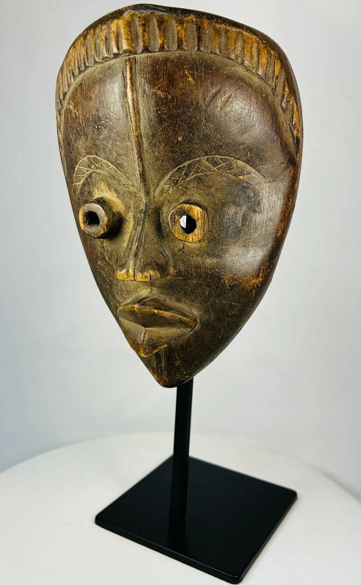 Antique Baule mask from Ivory Coast featuring almond-shaped eyes and carved coiffure