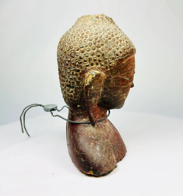 Angled view of carved Buddha sculpture with red lacquer and traces of gold gilding.