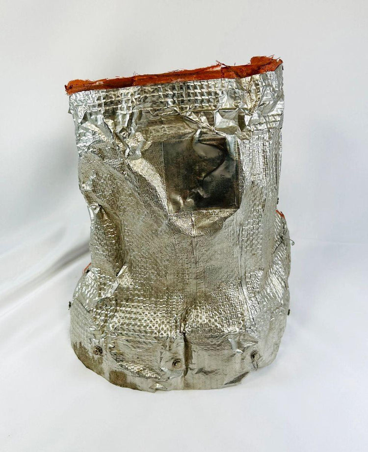 Flown NASA Space Shuttle insulation blanket made of reflective silver fibrous silica material with orange edge seal, used in the Orbiter Thermal Protection System, stamped April 1983 with visible serial and manufacturer markings, authentic aerospace artifact from the Space Shuttle Program, approximately 11 by 10 inches.