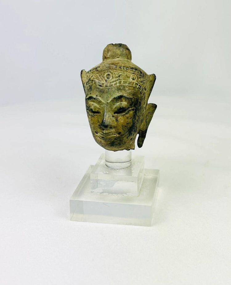 Front view of a Southeast Asian bronze Buddha head on display stand