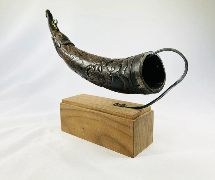 Side profile of carved Tibetan Buddhist horn with symbolic patterns.