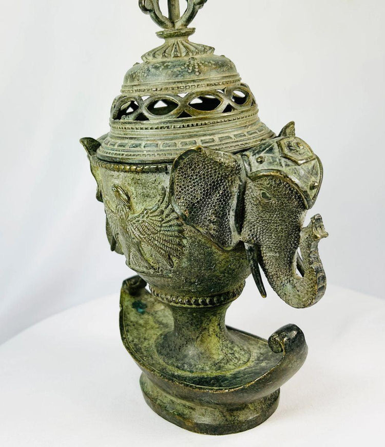Side view of an 18th-century Qing bronze incense burner showing detailed elephant-head handle and phoenix relief.