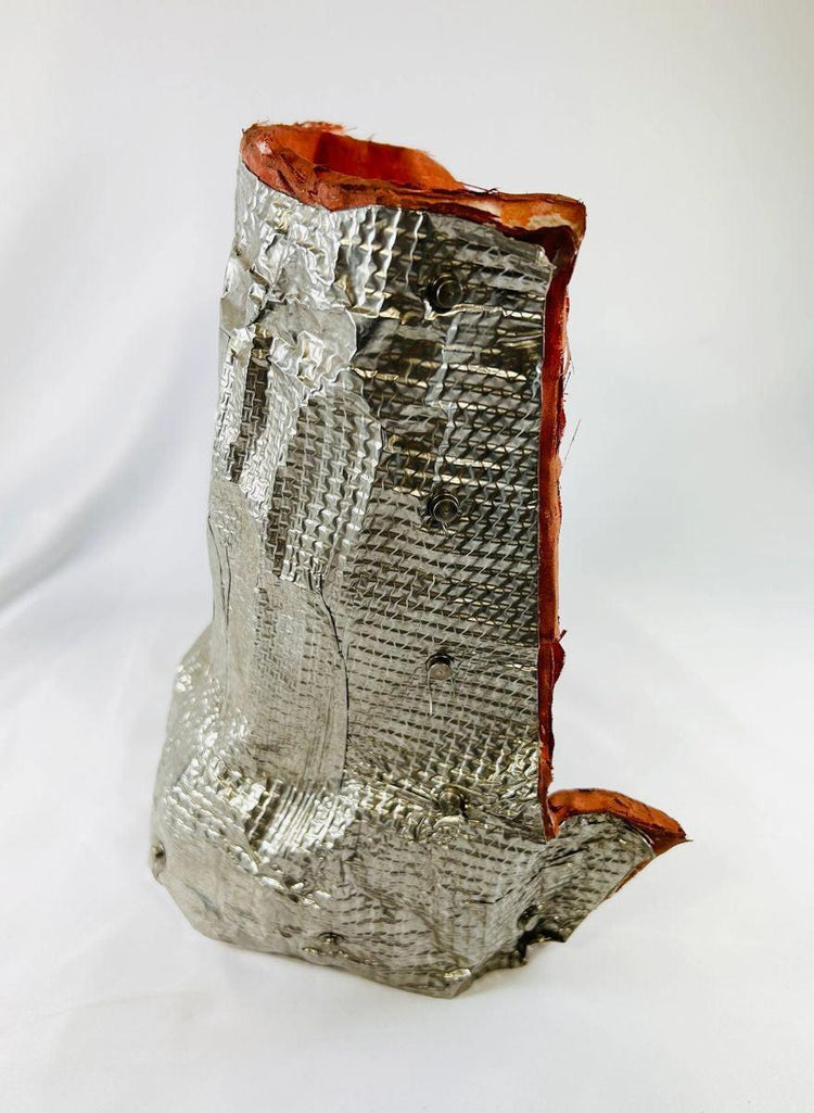 Authentic flown NASA Space Shuttle insulation blanket made of fibrous silica batting with reflective silver thermal surface and orange edge seal, used in the Orbiter Thermal Protection System (TPS), stamped April 1983 with serial number and manufacturer code visible on the metal tag, approximately 11 by 10 inches, aerospace artifact from the Space Shuttle Program.