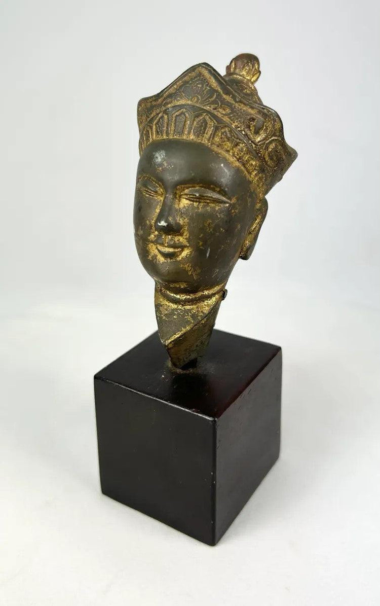 Tibetan Buddhist crowned Buddha head in gilded bronze, likely Avalokiteshvara, fragmentary sculpture with serene expression and surface wear from age.