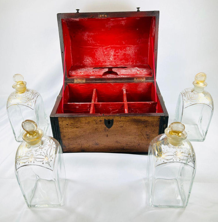 Early Georgian spirit box with red-lined interior shown open, surrounded by four matching gilt-decorated glass decanters.