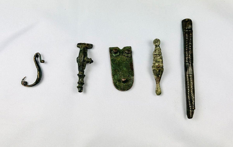 Assorted ancient Roman bronze artifact fragments including amulets, buttons, and decorative relics, 1st–12th century AD.
