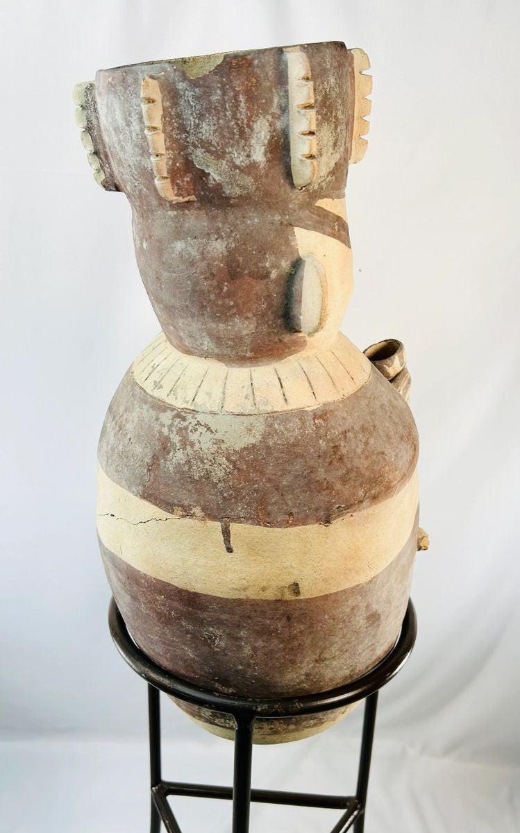 Rear view of Chancay terracotta effigy urn from ancient Peru (1000–1400 CE), Pre-Columbian ceramic vessel showing sculpted human form, neck collar, and painted geometric bands, displayed on stand at Relic and Rarity.