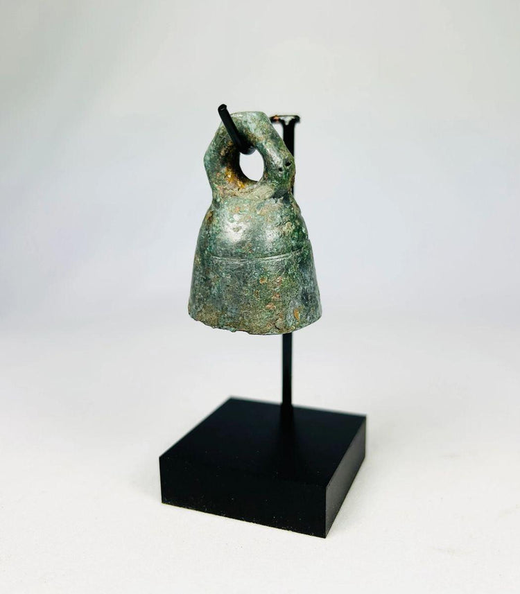 Close-up of Roman bronze bell showing textured green and brown patina from centuries of oxidation.