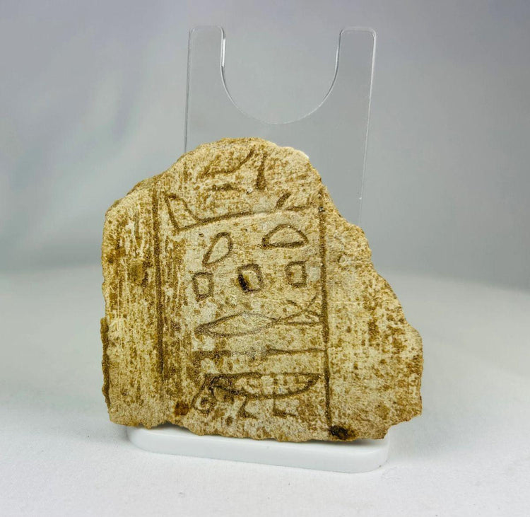 Egyptian hieroglyphic limestone fragment displaying vertical inscription and carved symbols.