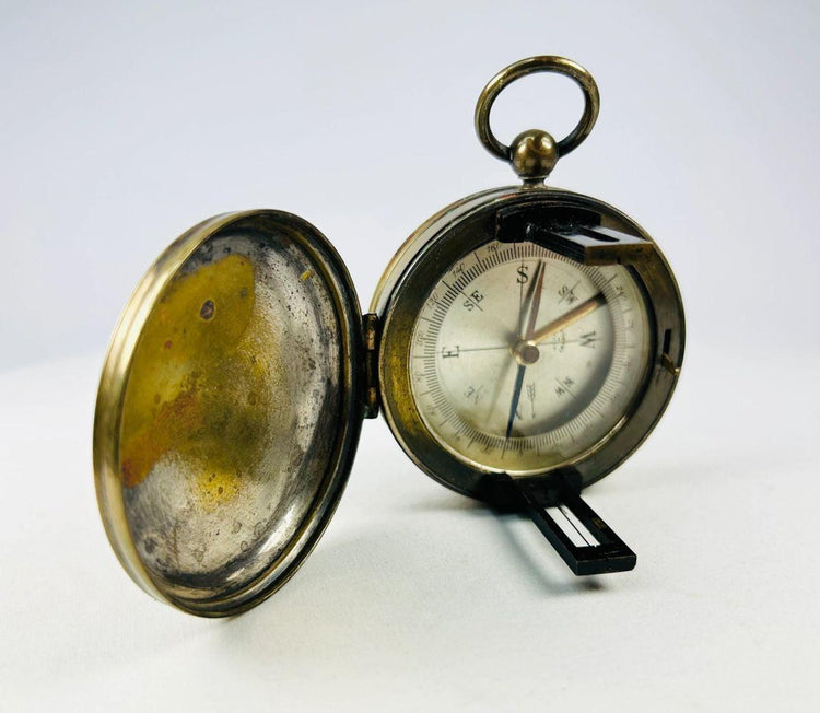 Early 20th-century French pocket compass photographed open to display magnetic needle and dial.