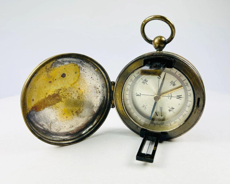 Antique French brass pocket compass shown open with hinged lid and glass-covered dial.