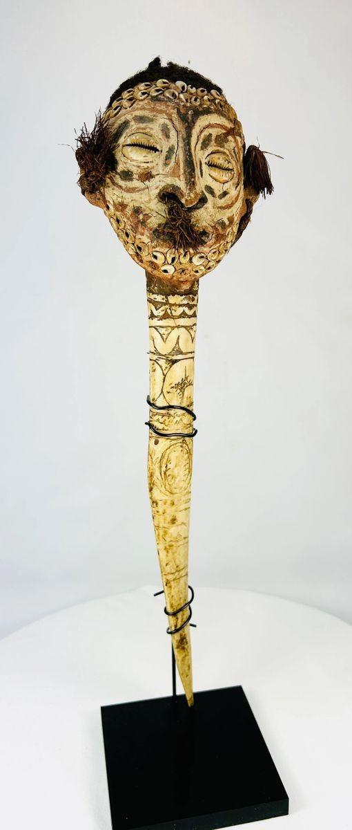 Full-length Sepik River bone dagger on display stand, highlighting carved motifs, anthropomorphic head, and ceremonial patina.