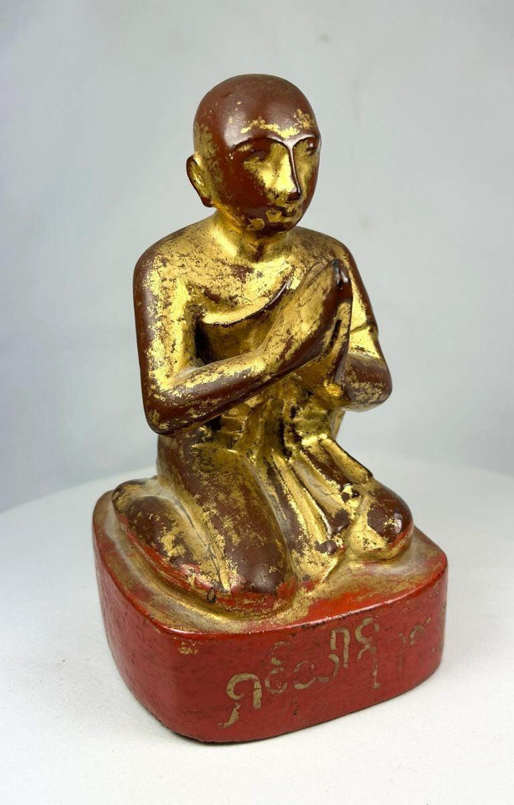 Close-up of monk’s serene facial expression with traces of gold leaf and traditional Burmese craftsmanship.