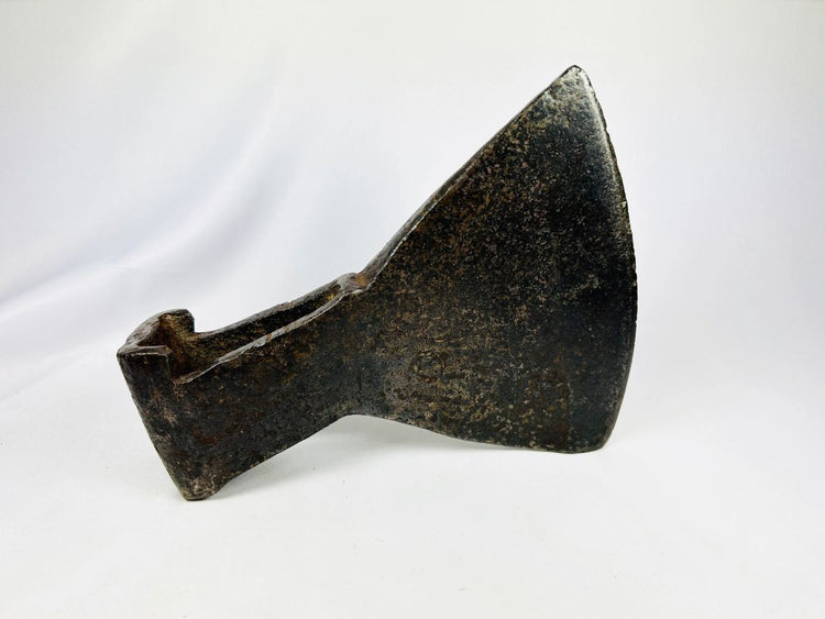 18th-century cast iron axe head with wedge-shaped blade and aged patina.