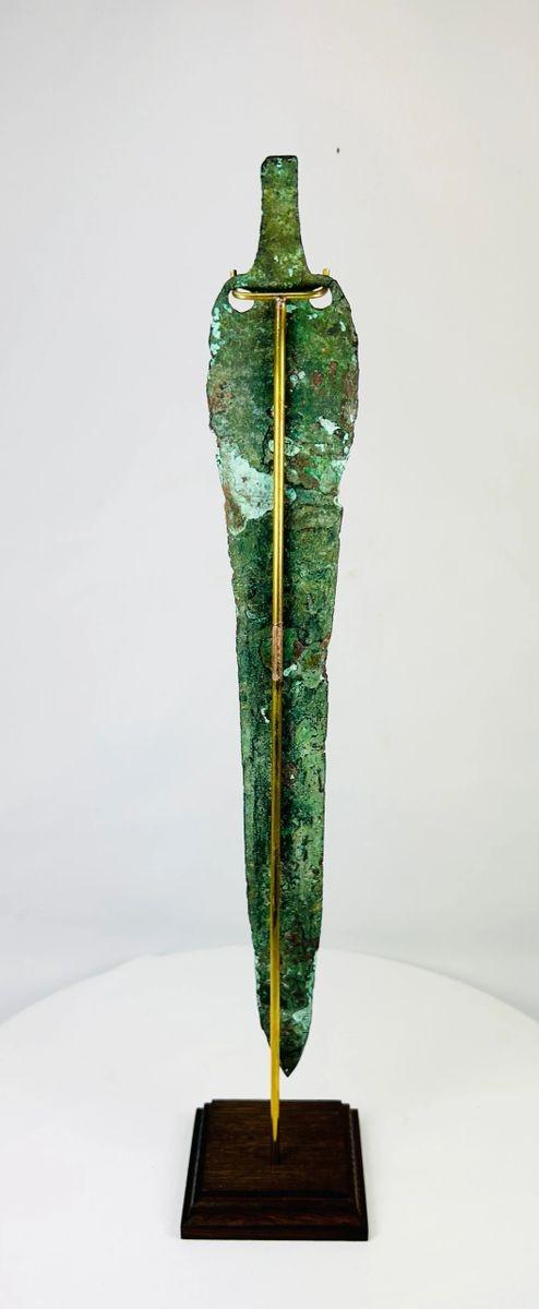 Bronze Age Persian blade from Caspian region, angled view revealing curved edge and ancient corrosion.