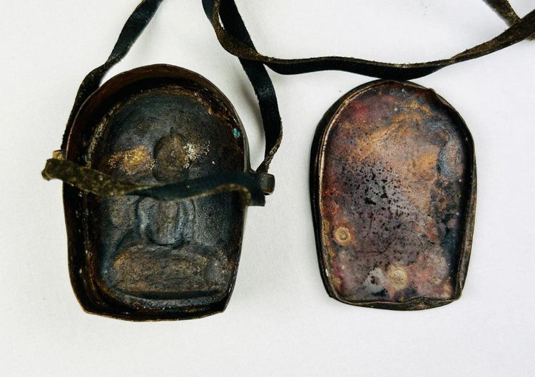 Tibetan Buddhist amulet box displayed on neutral background showing devotional details.