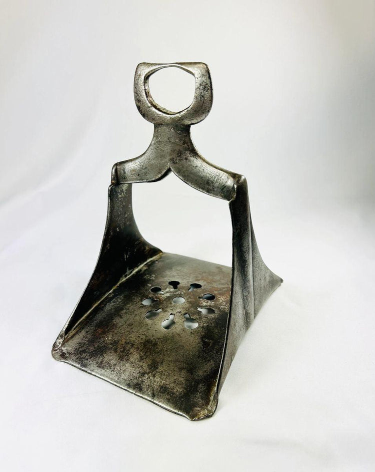 Historic Ottoman stirrup with floral perforated footplate and curved suspension loop, photographed upright.