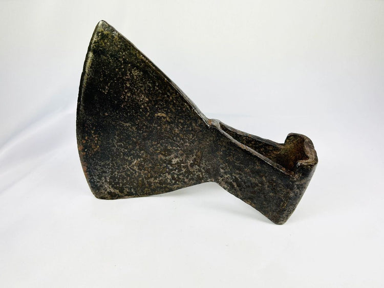 Close-up of 18th-century iron axe head surface texture and maker’s punch mark.