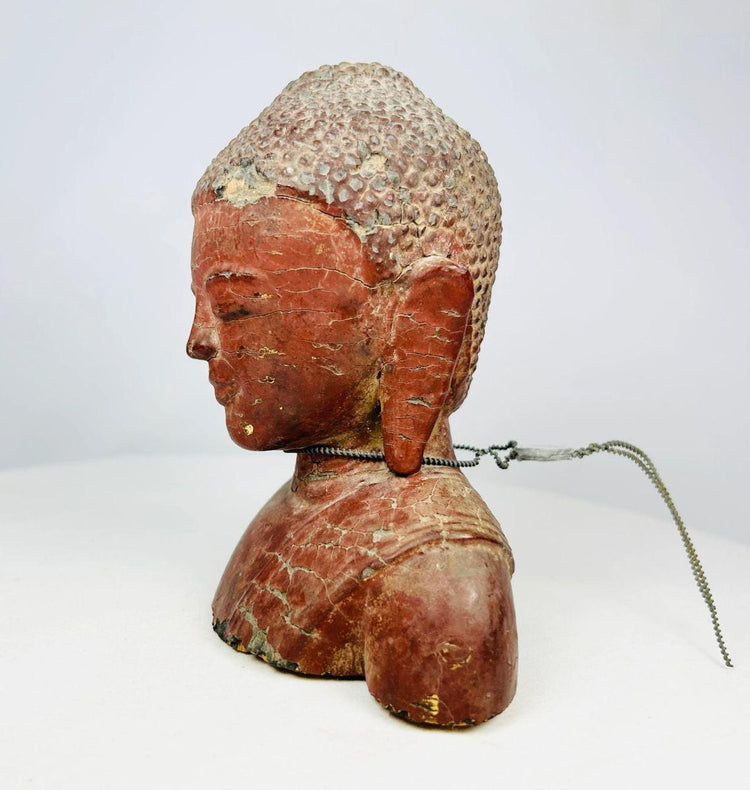 High-resolution image of Buddhist wooden sculpture with ceremonial metal loop and chain.